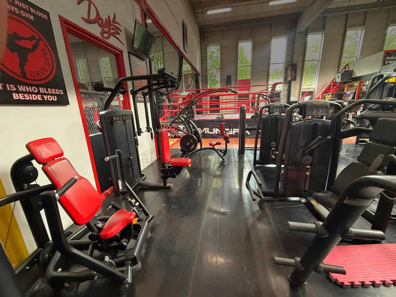 Krachtmachines met rode bekleding naast de posters van Days Gym