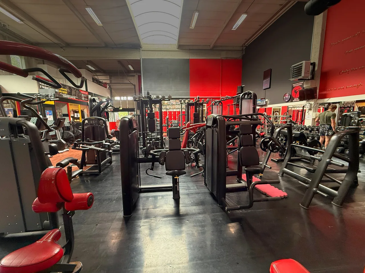 Overzicht van de fitnessvloer met krachtmachines en kabelstations